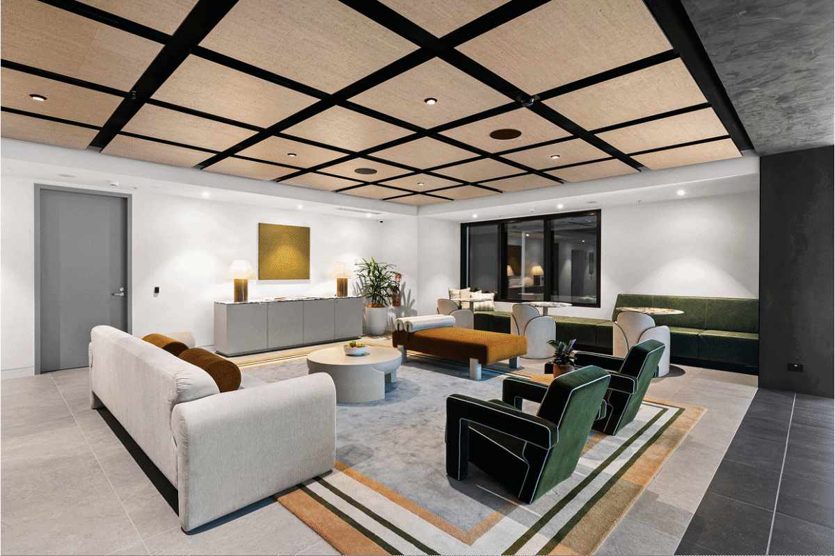 Elegant modern lounge styled by BOWERBIRD Interiors, featuring soft neutral sofas, deep green armchairs, and a geometric ceiling design that complements the contemporary palette.