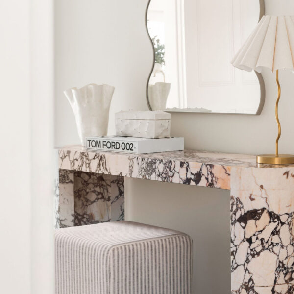 Marble console table with wavy mirror and gold lamp in modern entryway