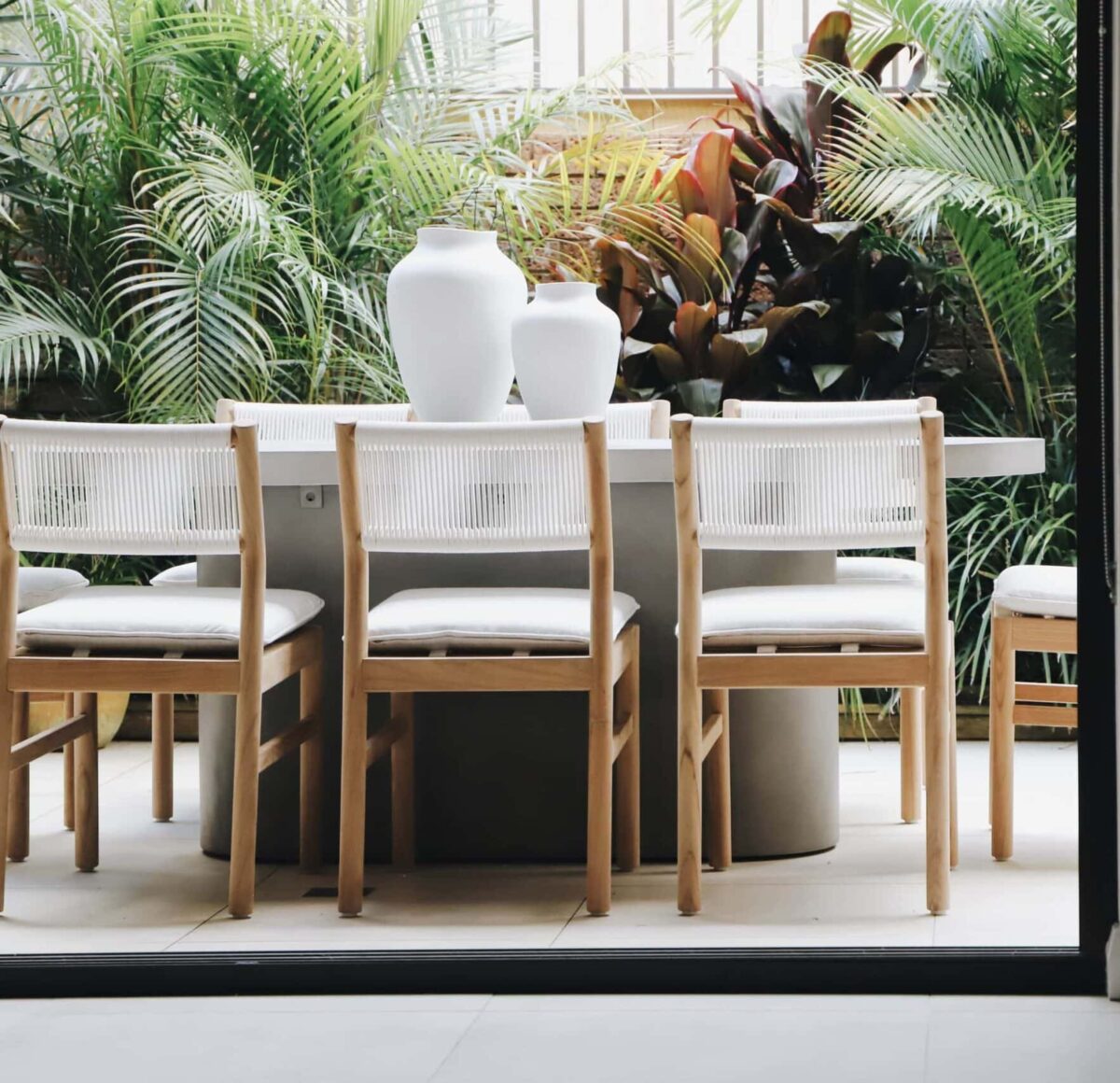 Outdoor Dining With Concrete Table, Wood Chairs, and Tropical Plants