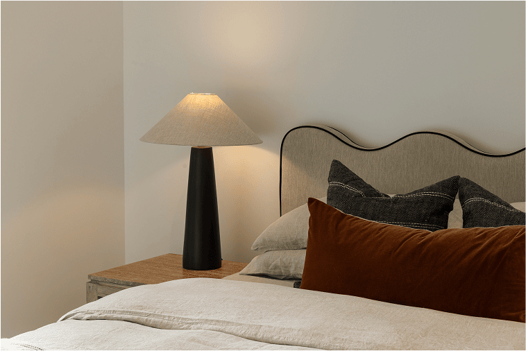 Master bedroom staged for sale with layered bedding and soft lighting